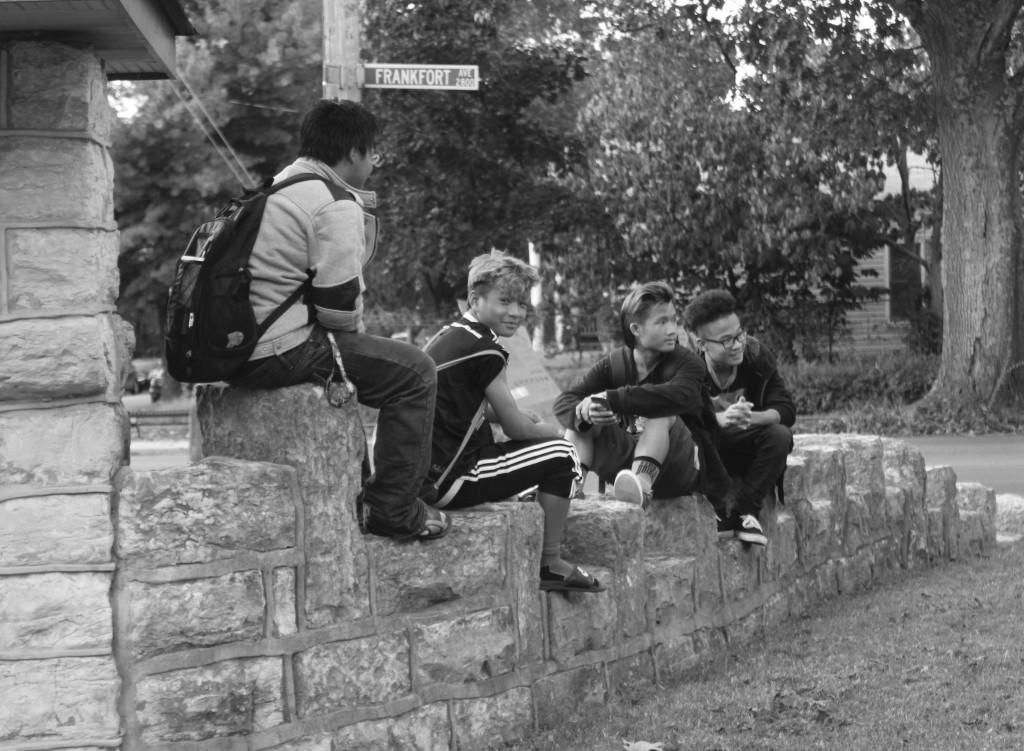 Observing the Crescent Hill Baptist Church youth group playing elbow tag, four of the youth gather on a wall and laugh. Photo By Sam Sims. 